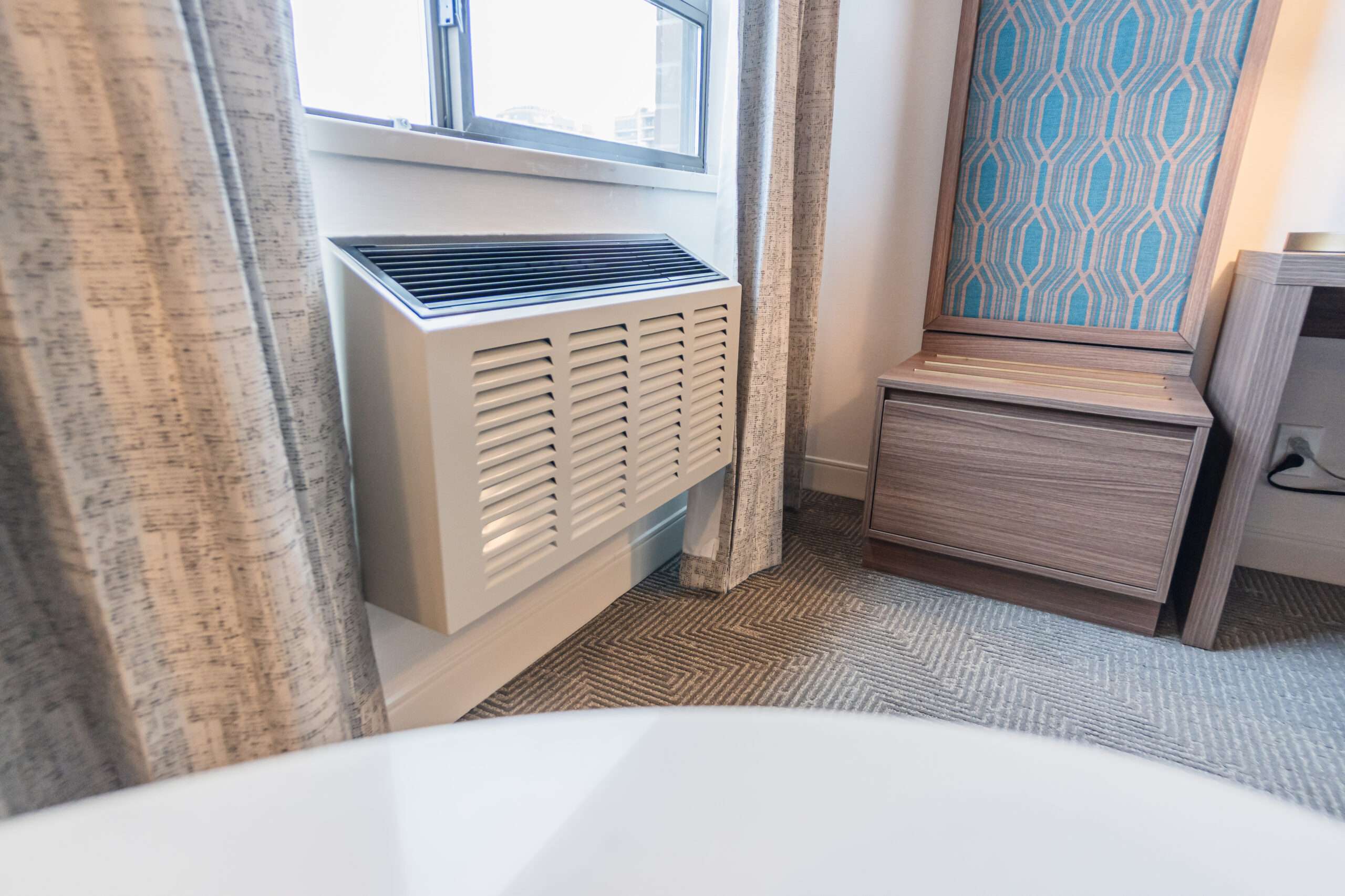 A bathroom with a window and a white air conditioner.